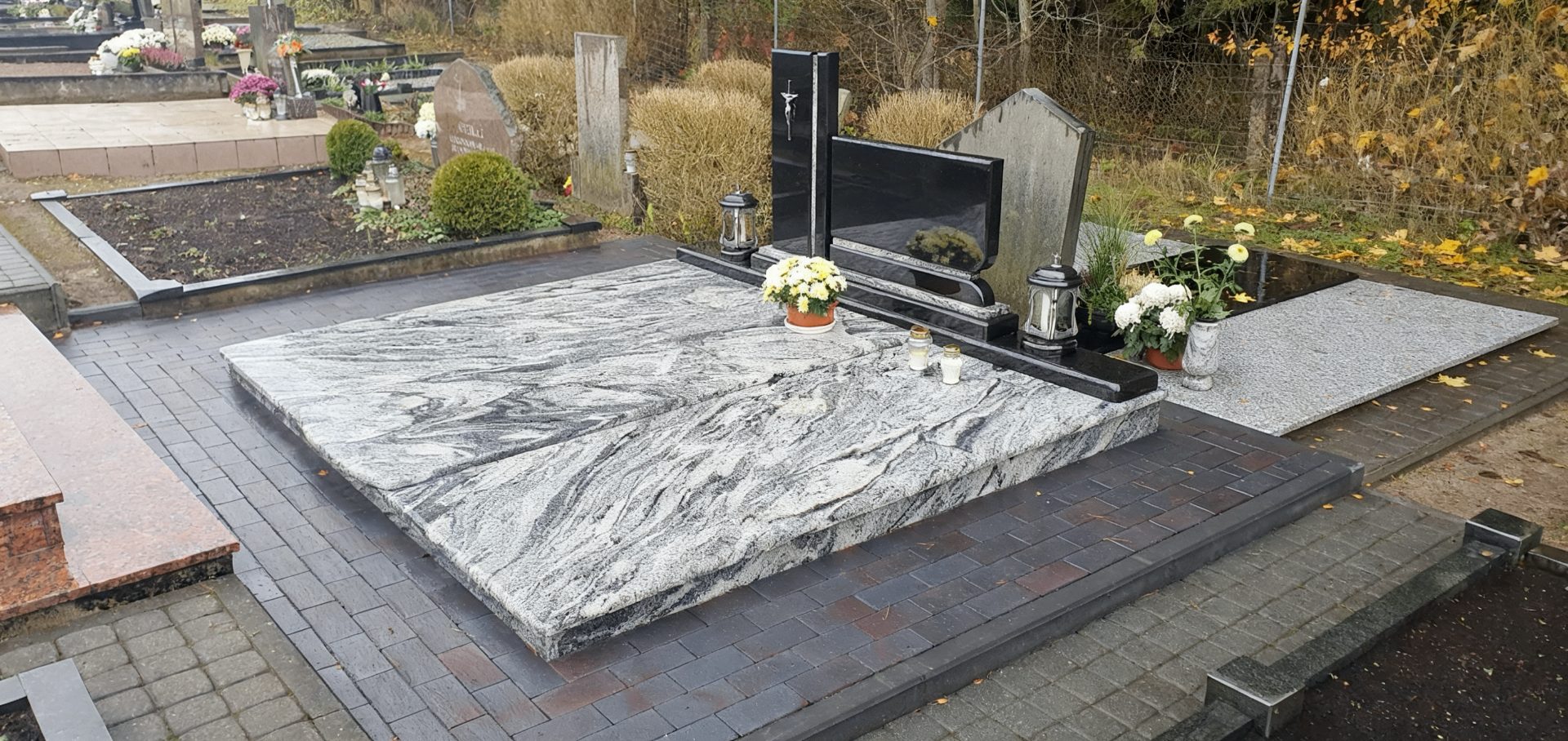 Pilko granito kapavietė su juodu paminklu ir žvakidėmis